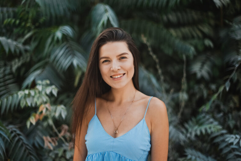 Portrait of young and beautiful woman with perfect smooth skin in tropical leaves.