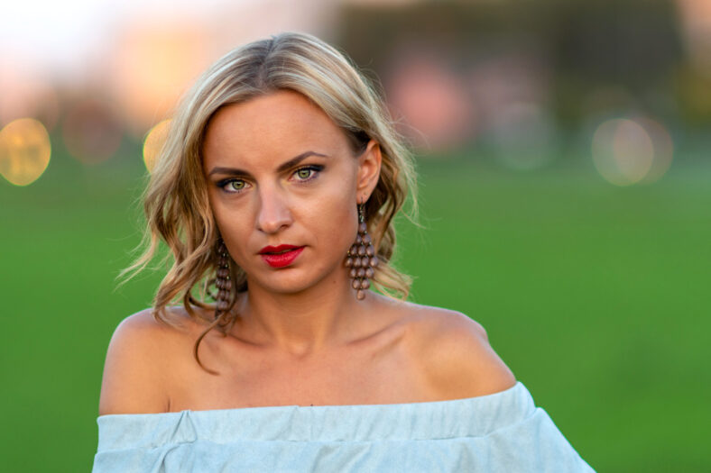 Soft focus photo. A portrait of a young, beautiful blond woman on a green background.
