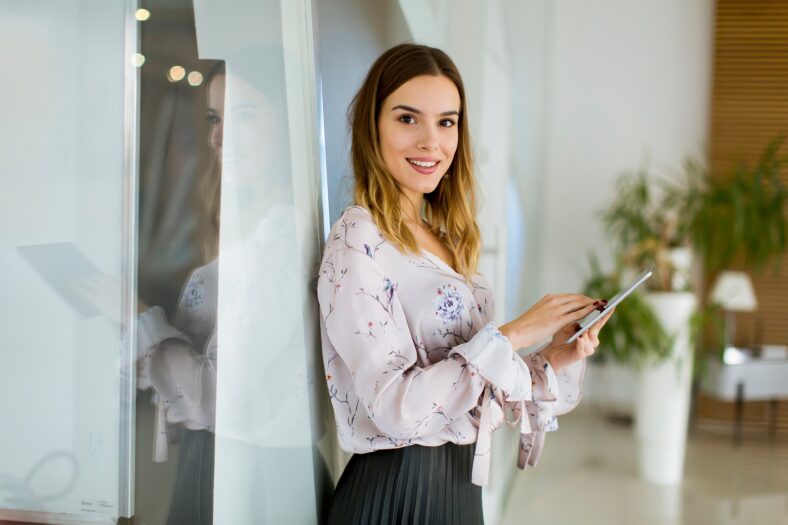 Attractive young businesswoman using a digital tablet while standing in the office