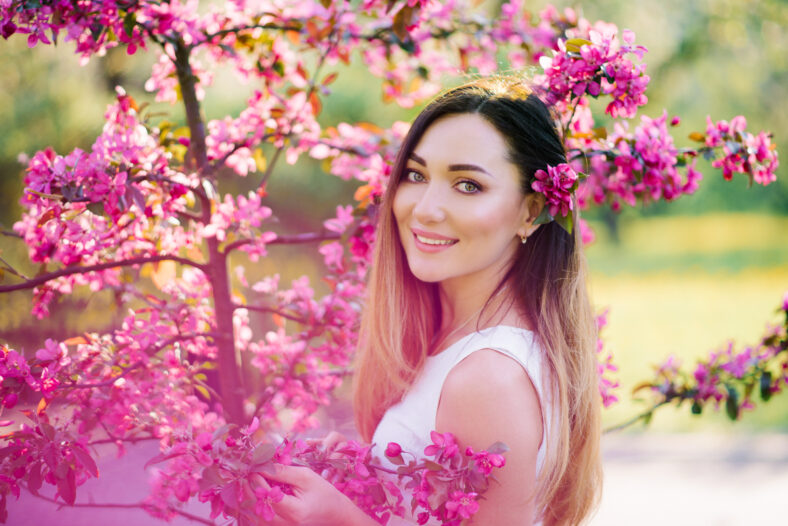 Beautiful girl with color hair Ombre is in blossoming pink tree in the spring and . Beautiful eyes and a pretty face.