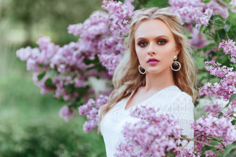 Beautiful woman enjoying lilac garden, young woman with flowers in green park. cheerful teenager walking outdoor. soft light style color.