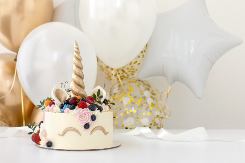 Close up of little girl's birthday party table with unicorn cake