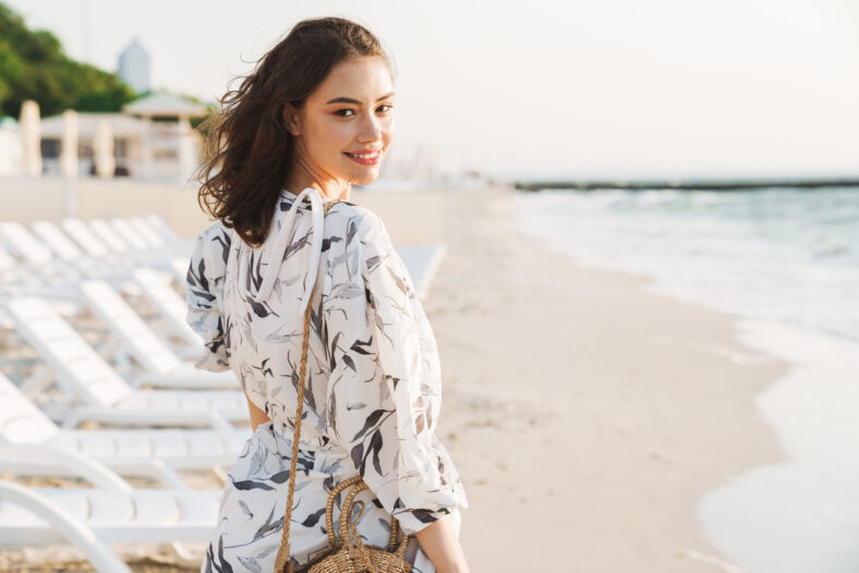 Back view image of a pleased happy young beautiful woman at the beach running in a beautiful sunny morning.