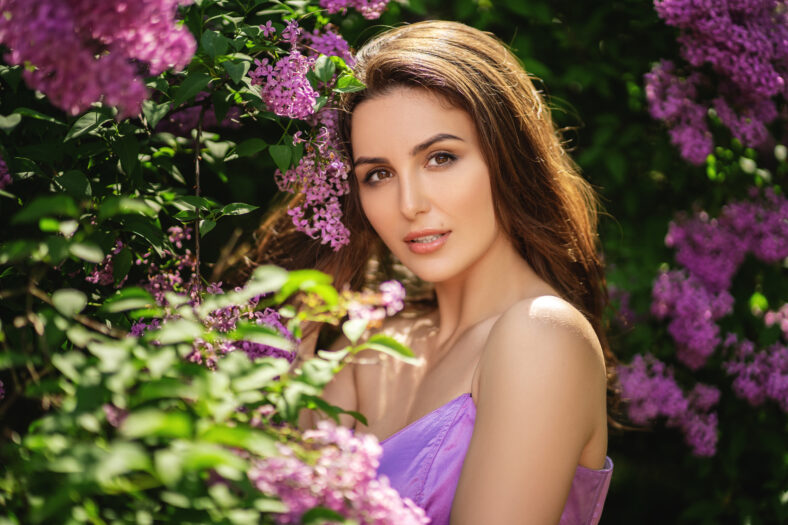 Close up portrait woman near a blossoming lilac tree.