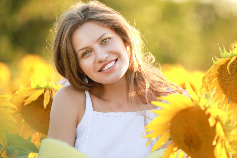 Hermosa mujer joven en el campo de girasol el día de verano
