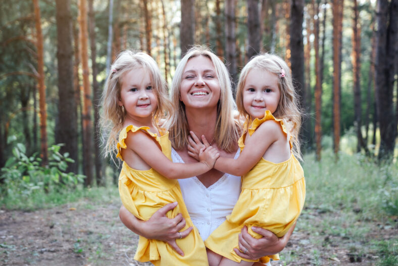 Happy mother with two little twin daughters