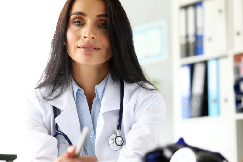 Female GP sitting at worktable in office looking in camera portrait