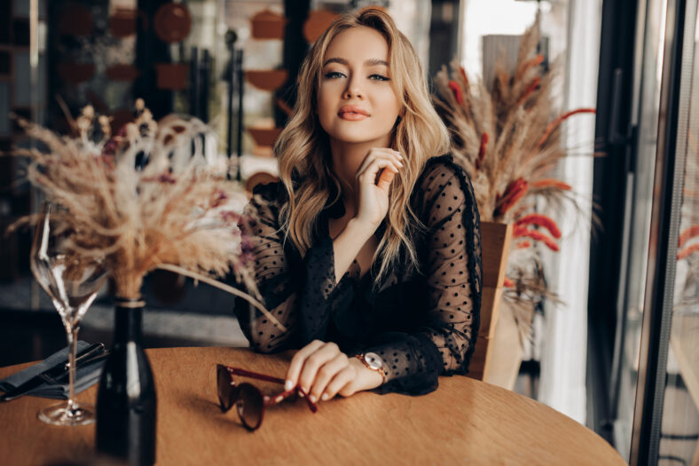 Beautiful Woman Posing in the interior. Fashionable young Woman with perfect make-up and blonde curly hair. 