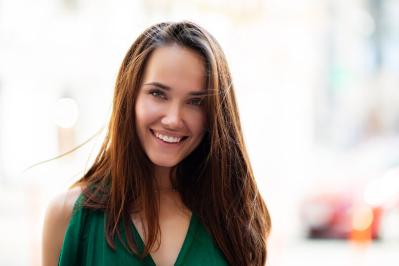 Fashion model wearing green overall posing outdoor. Young beautiful brunette caucasian woman walking summer streets. Beautiful girl, urban portrait.