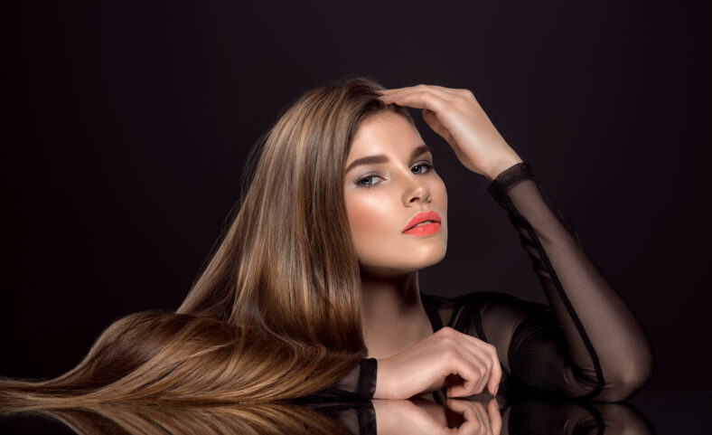 Woman with beauty long brown hair. Fashion model with long straight hair. Fashion model with a smokey makeup. Pretty woman with living coral color lipstick on lips. Pantone 2019. Living coral.