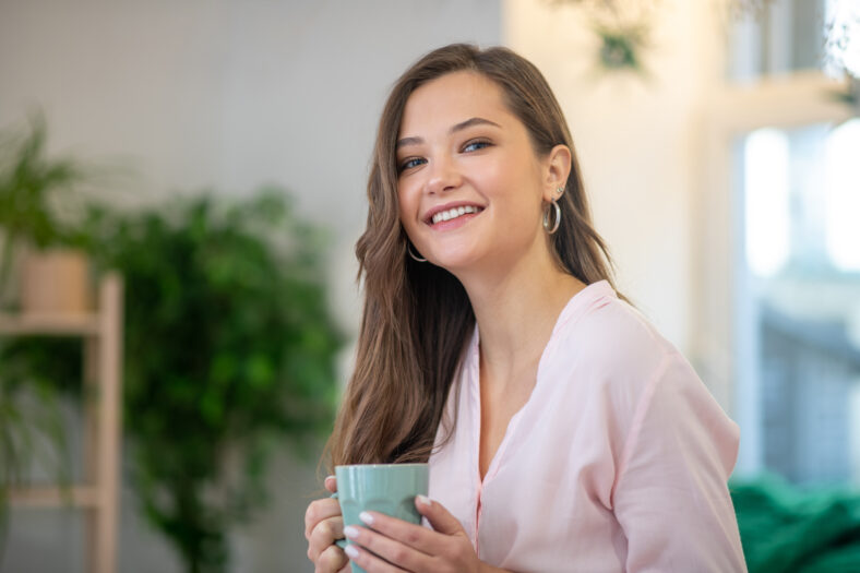 Full of energy. Face of a joyful young woman feeling full of energy while drinking coffee