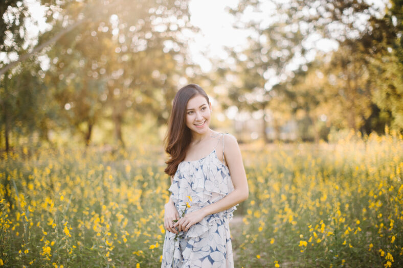 happy young woman enjoying summer in yellow flower field