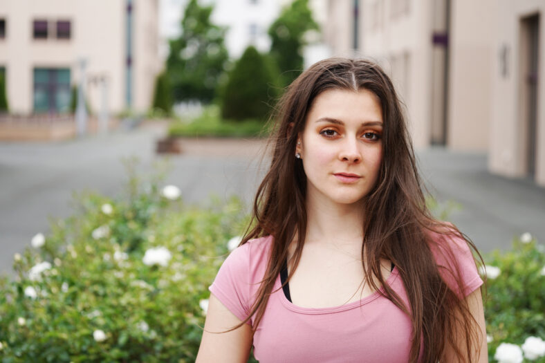 street portrait of a serious young woman with long brunette hair outdoor. Beautiful young female in an urban setting with copy space