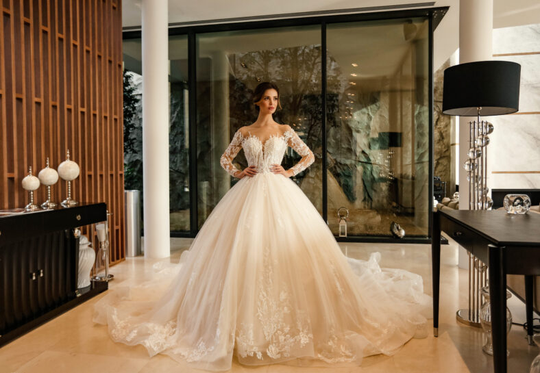 fashion interior photo of beautiful bride with dark hair in elegant wedding dress posing in luxurious interior