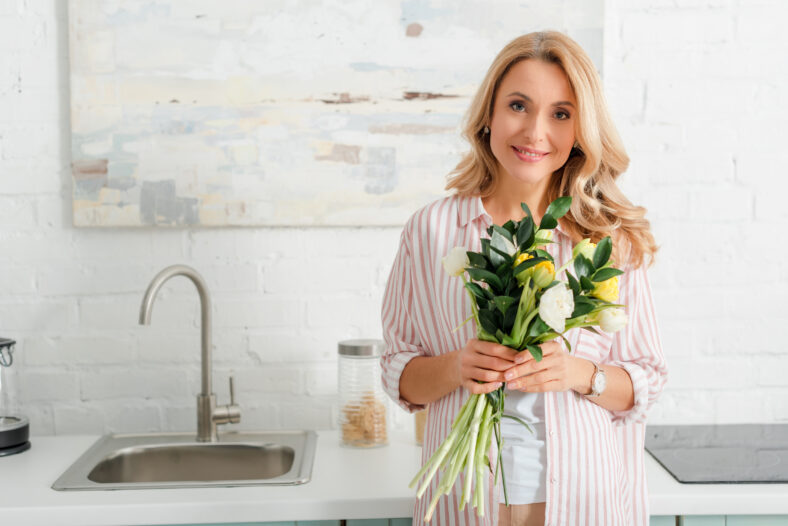 happy woman holding bouquet of tulips and looking at camera