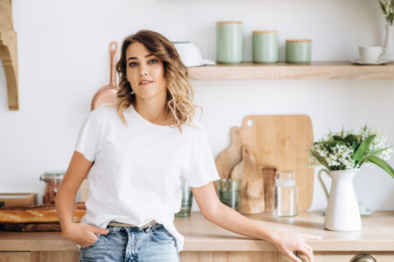 Attractive young girl in stylish casual clothes posing in the kitchen at home