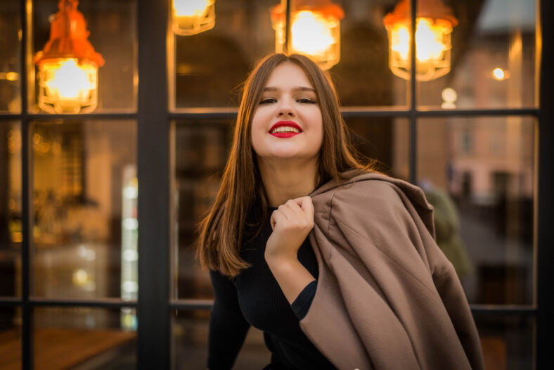 Headshot Portrait of happy teenage ginger girl with smiling looking at camera. City cafe light background. Bright makeup.