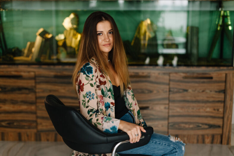Stylish brunette woman sitting at home in the background aquarium
