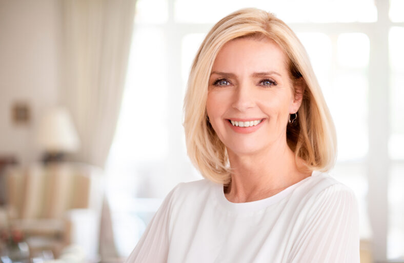 Close-up portrait of beautiful blond woman standing indoor.