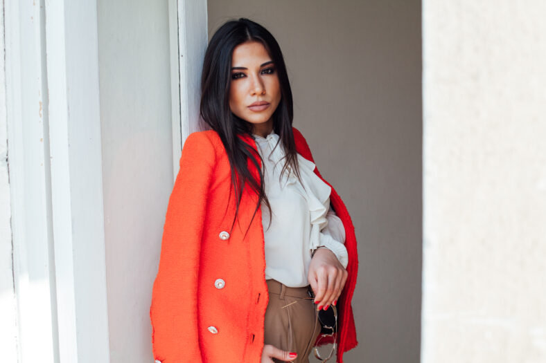 Portrait of a beautiful oriental fashionable brunette woman in a business suit with an orange jacket