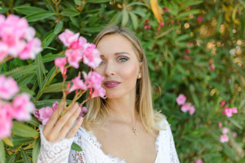 Portrait of a beautiful bride in a white dress in a bush of flowers.