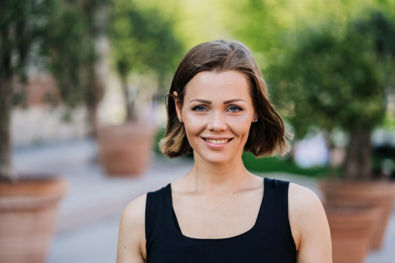 Gorgeous young woman with short hair dressed casual with confidence and pretty smile walking in park. Girl satisfied with her lifestyle, fitness and her job. Success people concept.