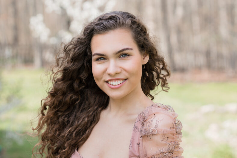 Young smiling woman with curly hair outdoor portrait
