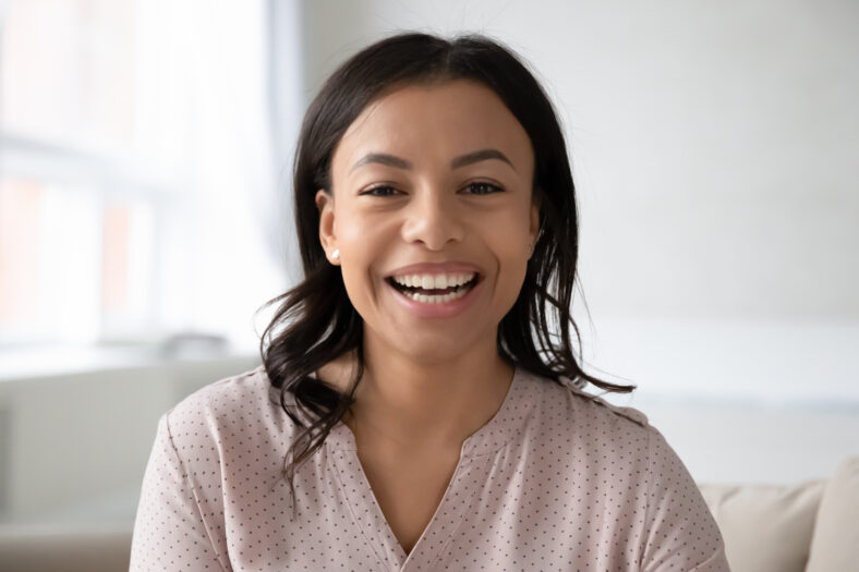 Head shot close up portrait African ethnicity woman sitting on couch takes part in videocall chatting with foreign friend webcam view, passes job interview distantly, blogger record new vlog concept