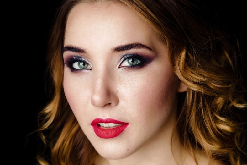 Portrait of gorgeous young woman on dark background. Sensual young woman with red lips and bright makeup. Beautiful healthy face of the young pretty woman with fresh skin.