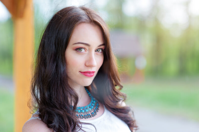 Outdoors portrait of beautiful young brunette woman looking at camera.