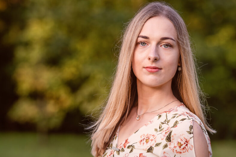 Portrait of a young blonde woman against a defocused landscape. Autumn color shade - image
