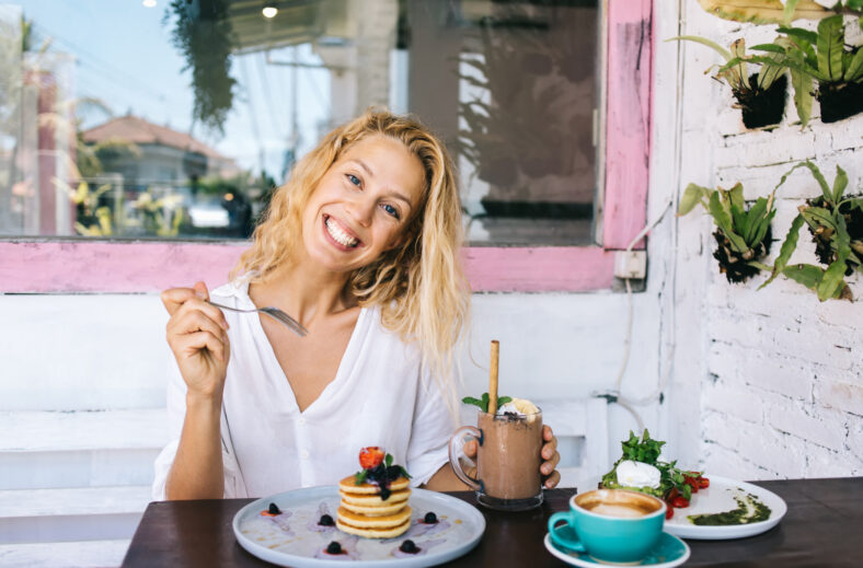 Half length portrait of cheerful caucasian blonde female having lunch break eating healthy meal for keeping perfect body shape,positive pretty hipster girl satisfied with tasty food for breakfast