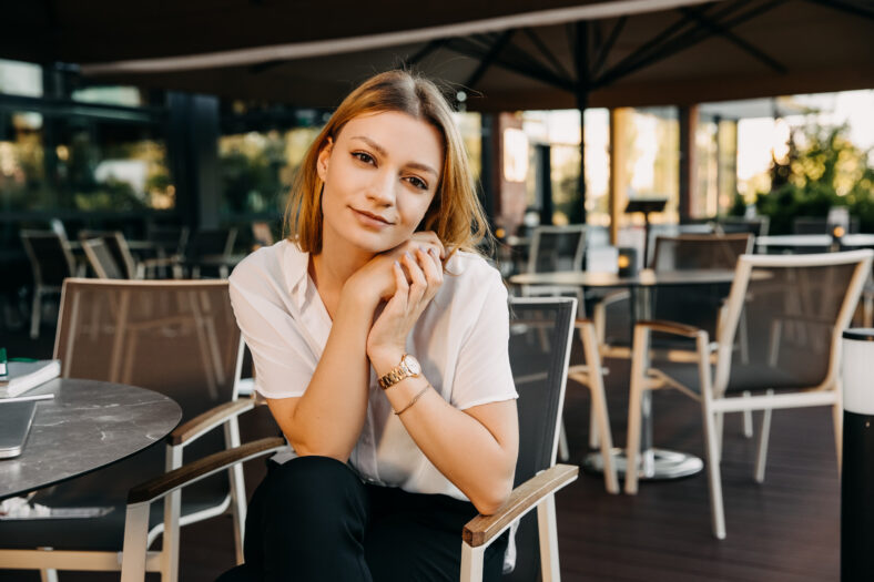 Young pretty woman, wearing a white shirt, looking to camera, smiling.