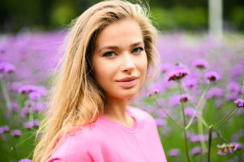 Young woman portrait posing against purple flowers