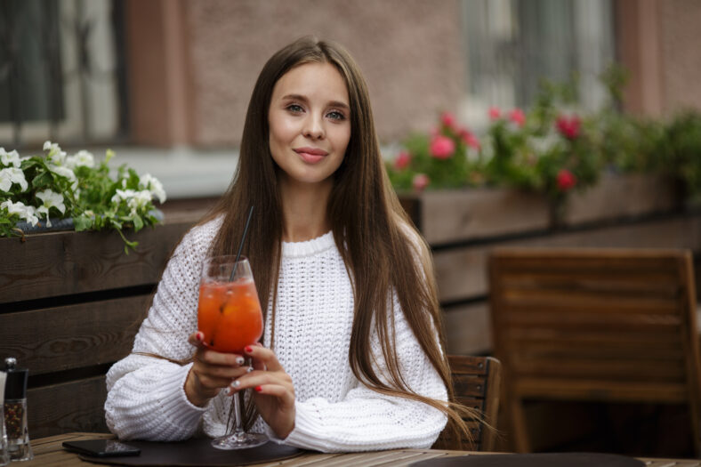 Young beautiful woman in a cafe holding a soft drink. Copycpase