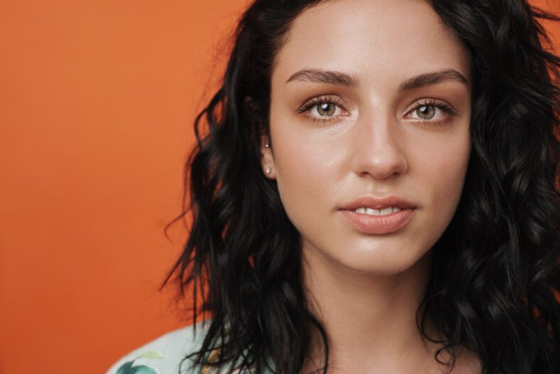 Image of young pleased positive smiling woman isolated over orange wall background
