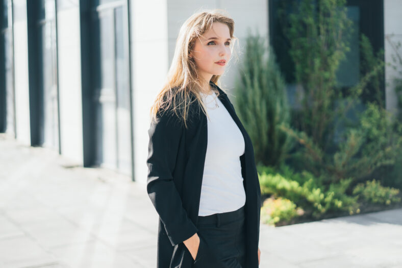 a cute blonde in a business black suit walks around the territory of a business center