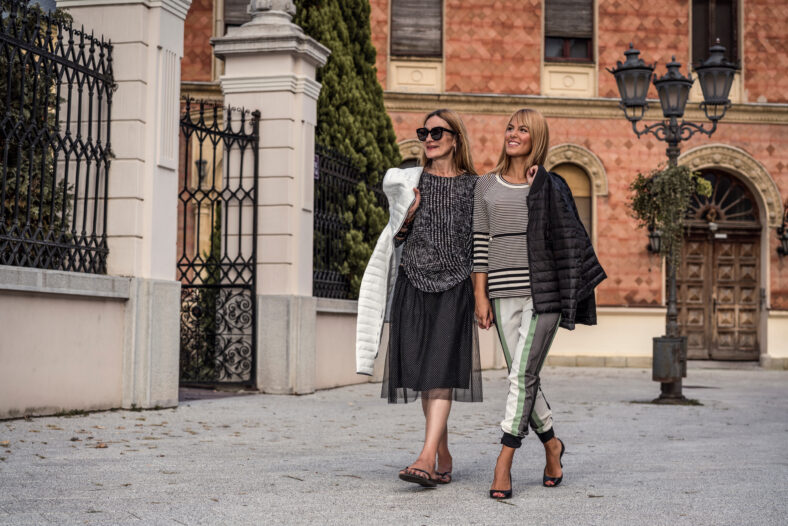 Beautiful and fashionable mature mother and young daughter outdoors in city with fresh new clothes. Fashion for mothers and daughters. Happy mother and daughter love. Family love.