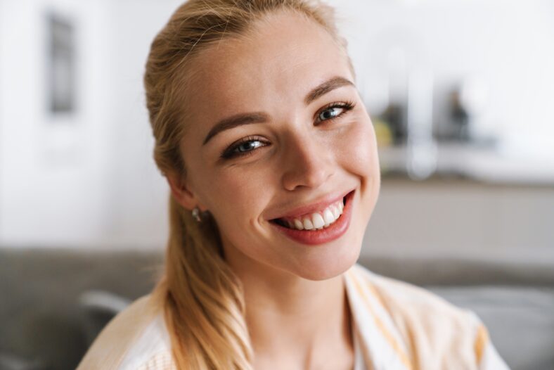 Happy blonde woman smiling and looking at camera at home