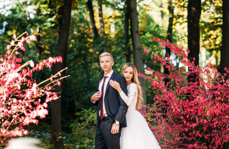 the bride and groom are walking in the autumn park