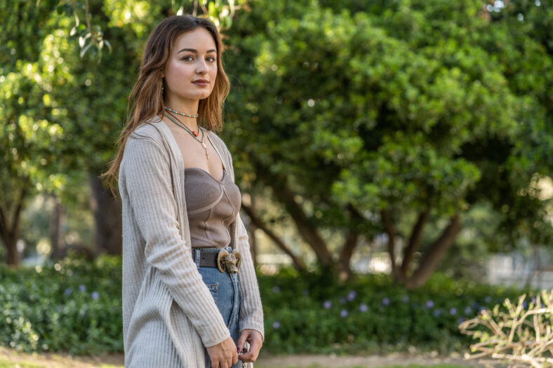Pretty caucasian young woman in a public park with background of trees