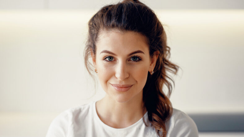 Mira la cámara. Retrato de una mujer cercana de apariencia europea. La hermosa morena sonríe.