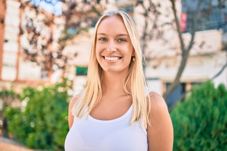 Young blonde girl smiling happy walking at the park.