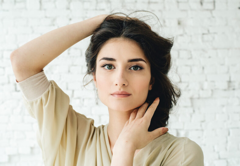 Hermosa mujer morena con cabello largo ojos de belleza de la cara sobre la pared de ladrillo