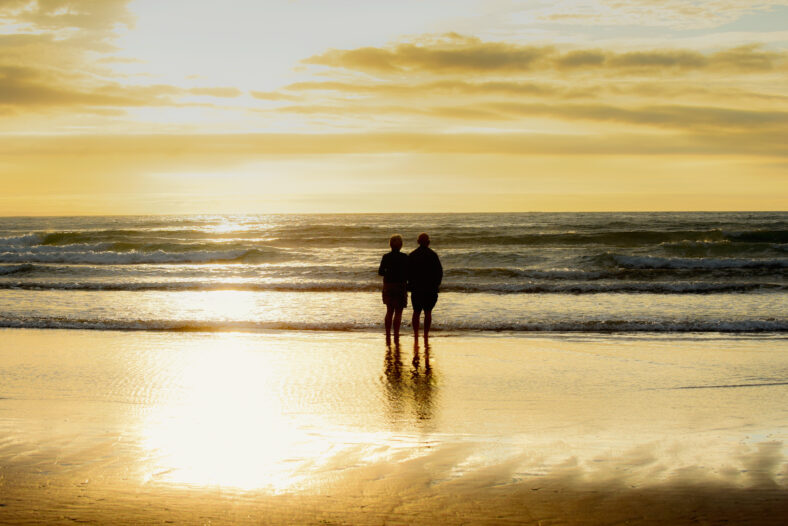 Paras románticas de la edad de jubilación que miran al mar al atardecer