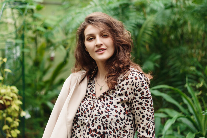 Beautiful pretty girl in a leopard blouse on a background of green jungle.