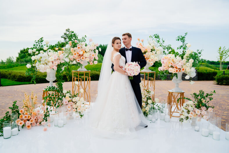 beautiful bride and groom in the wedding ceremony area of live white and pink flowers. decoration and organization of celebrations in the open air.