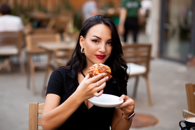 Beautiful woman drinking coffee in a cafe and eating croissant.