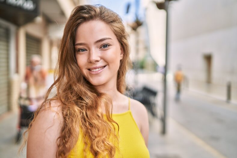 Joven caucásica sonriendo confidencial en la calle
