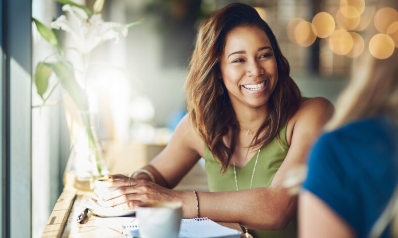 Cropped shot of a woman chatting to her friend in a cafe